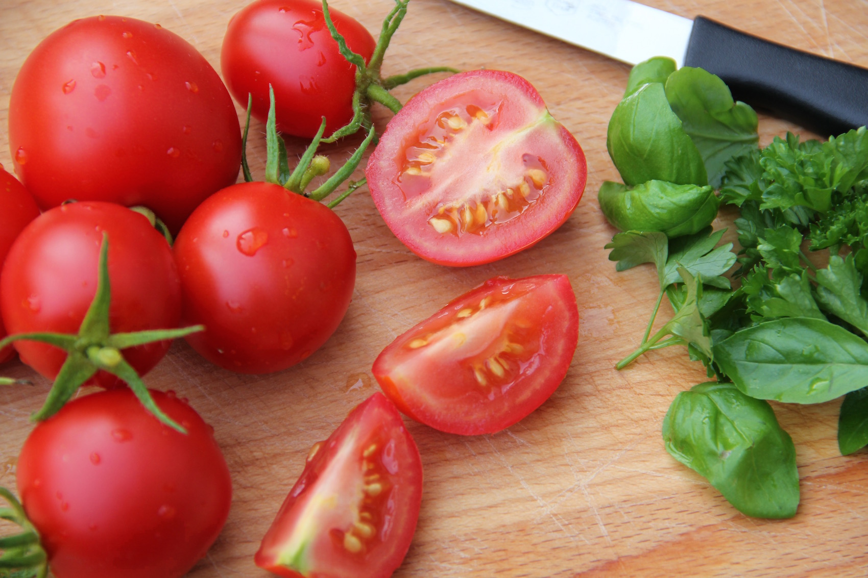 Tomaten und Kräuter auf einem hölzernen Küchenbrett